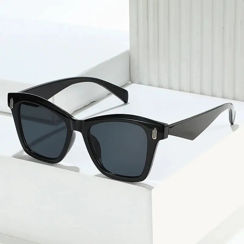Cat-eye sunglasses with a glossy black frame, dark grey lenses, and retro rivet accents – Astroshadez