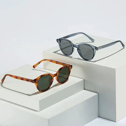 Two round sunglasses: blue-gray translucent frame with dark lenses, and tortoiseshell frame with green lenses – Astroshadez