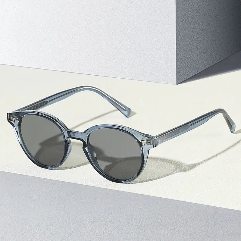 Round sunglasses with translucent blue-gray frame and dark gray lenses; retro rivet accents – Astroshadez