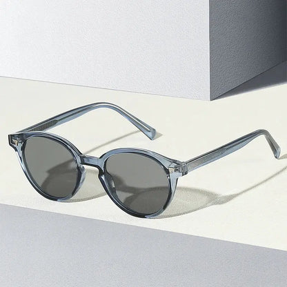 Round sunglasses with translucent blue-gray frame and dark gray lenses; retro rivet accents – Astroshadez